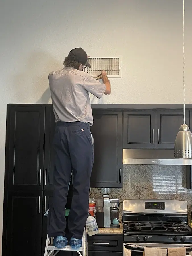 Technician inspecting an air vent during HVAC service in Colorado Springs